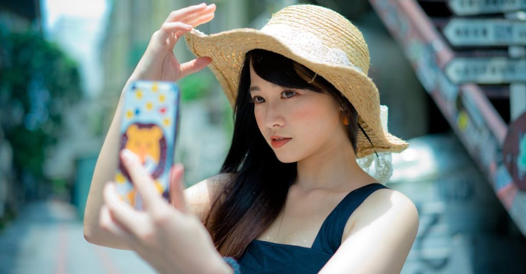 pexels-photo-1101597-1101597 Beautiful Asian woman in a straw hat taking a selfie on a sunny street in Taipei's Xinyi District.
