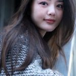 Portrait of a stylish woman outdoors in a modern urban environment, wearing a patterned sweater.