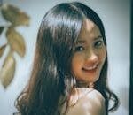 Portrait of a beautiful Asian woman with long hair smiling warmly, captured in an elegant studio setting.